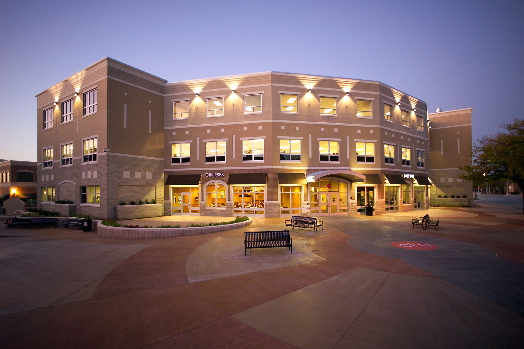 An exterior photo of the CIM Muskegon campus lit up at night against a dusky purple sky.